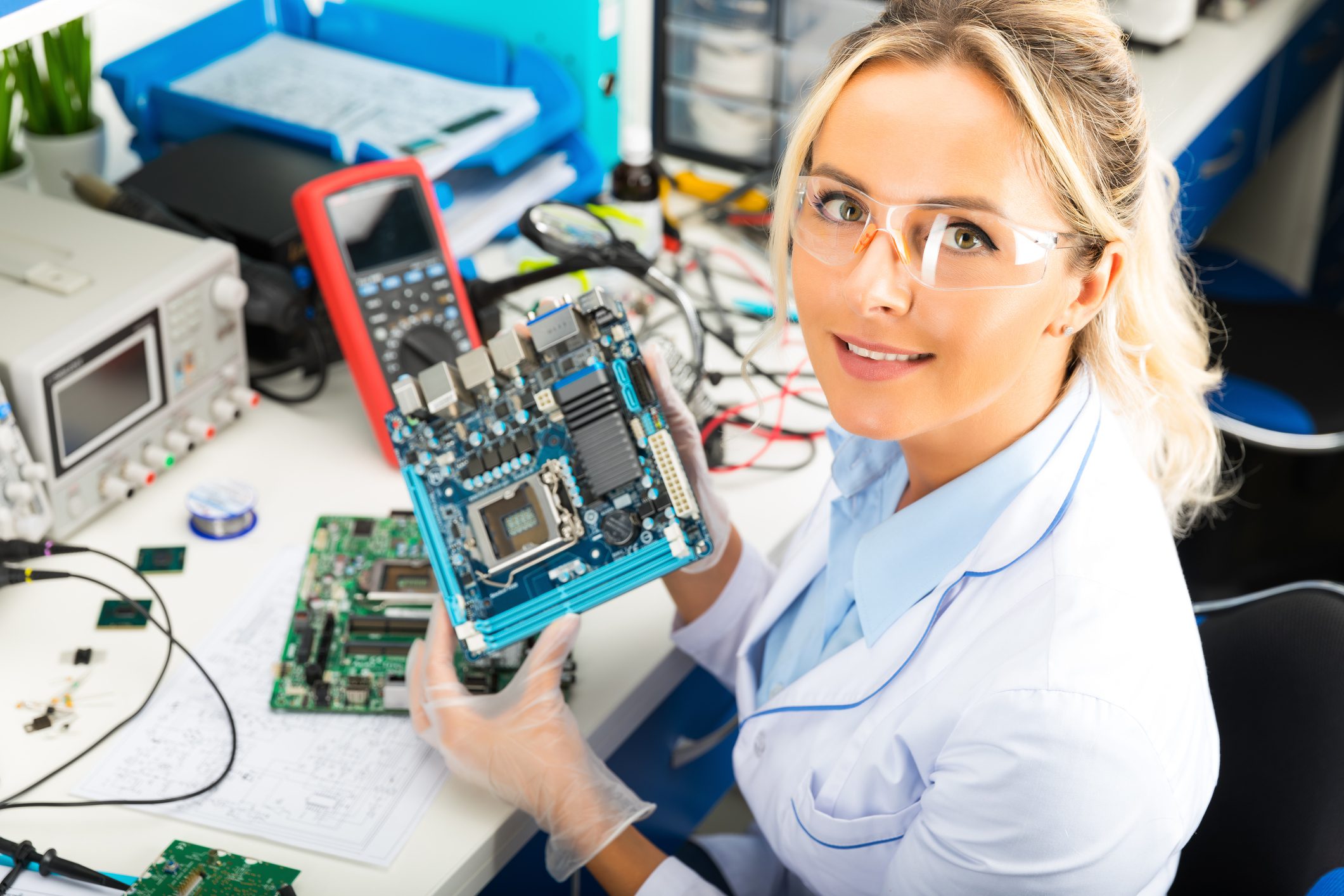 Engineer with safety glasses holding motherboard